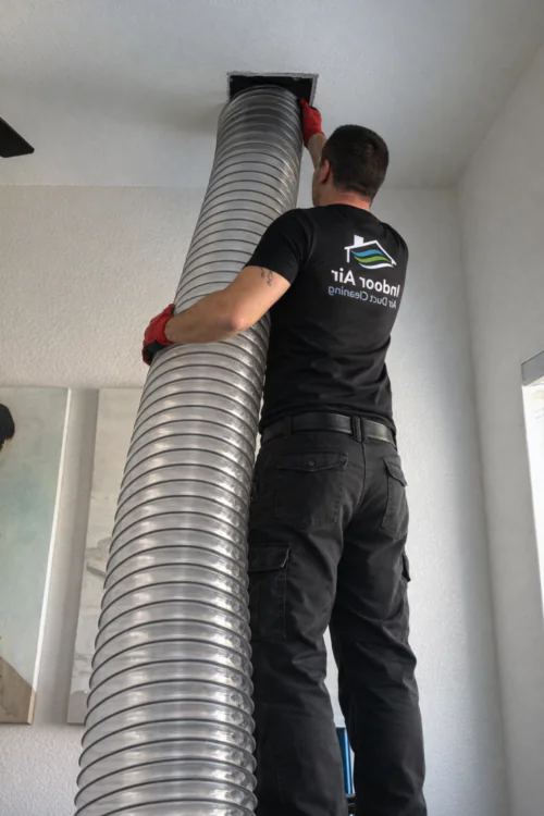Technician carrying a flexible air duct during an air duct cleaning job